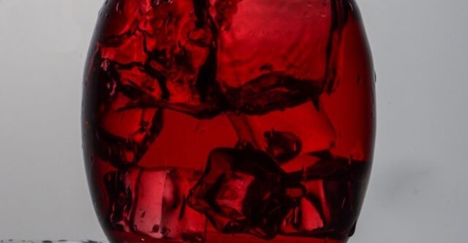 mano che agita eccessivamente il decanter con vino rosso