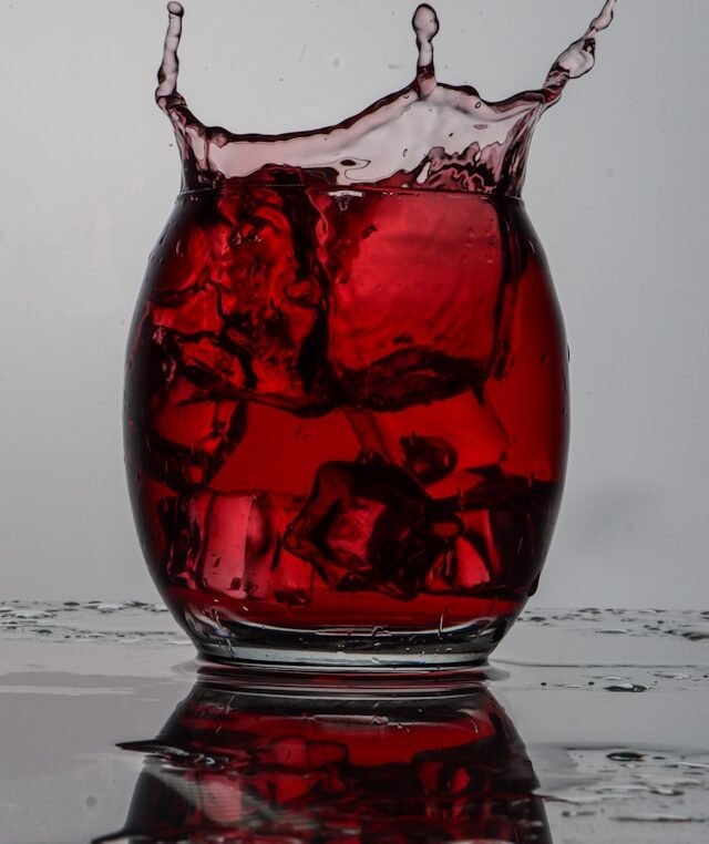 mano che agita eccessivamente il decanter con vino rosso