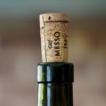 Bottiglia di vino aperta con tappo di sughero accanto a un bicchiere di vino rosso