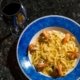 Piatto di pasta con pesce e bicchiere di vino rosso su tavola