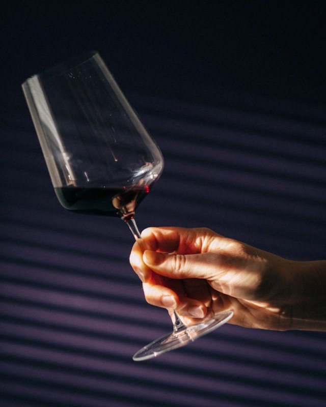 mano che ruota un bicchiere di vino rosso