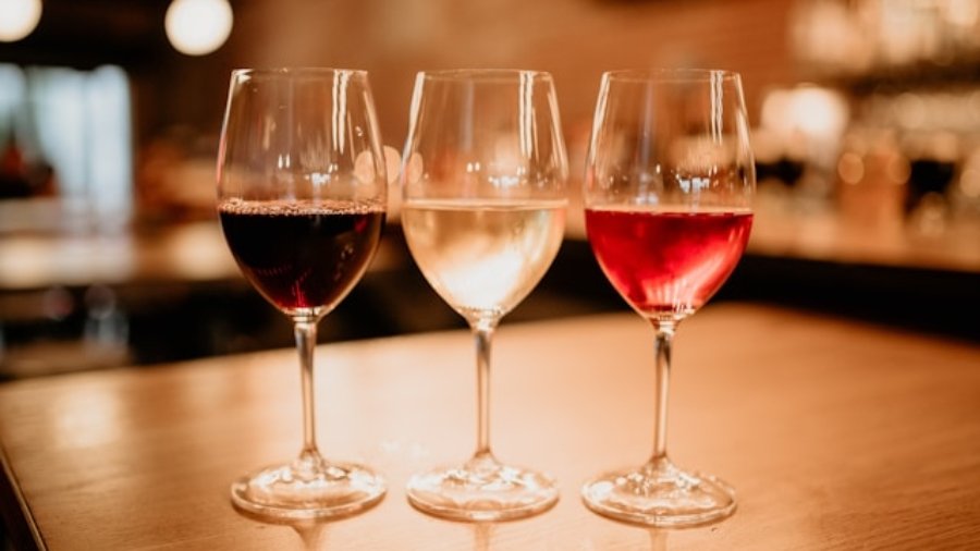 Bicchieri di vino rosso e bianco su tavolo in legno